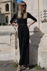 a lady in a black top and a pair of black pants with a belt